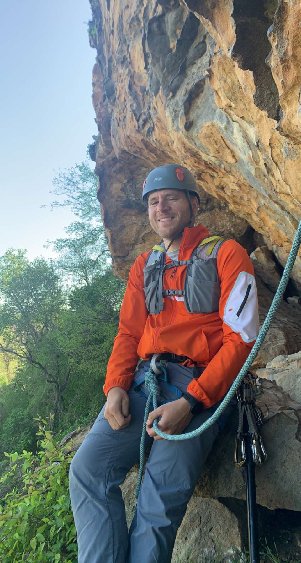 Andrew Taylor, owner of Sandstone Adventure Guides, leans against a rock face while wearing climbing gear. 